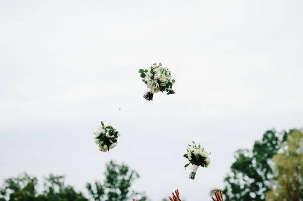 novia y damas de honor lanzando ramos de boda en el parque en el fondo del cielo. - flower toss fotografías e imágenes de stock