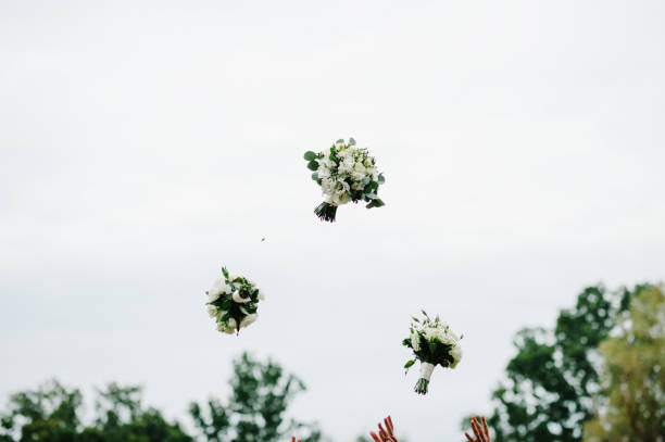 空の背景に公園で結婚式の花束を投げる花嫁と花嫁介添人。 - 投げる ストックフォトと画像