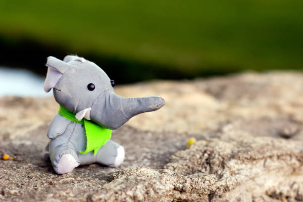 istock A toy elephant in a green tie as a scout sits on a stone. 1166079019