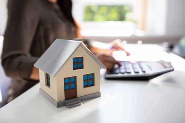 House Model In Front Of Businesswoman Close-up Of House Model In Front Of Businesswoman Calculating Invoice On Desk rood stock pictures, royalty-free photos & images