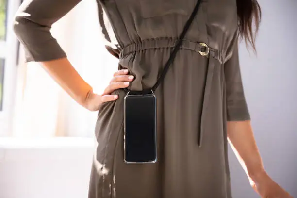 Mid-section Of Woman Carrying Mobile Phone In Office