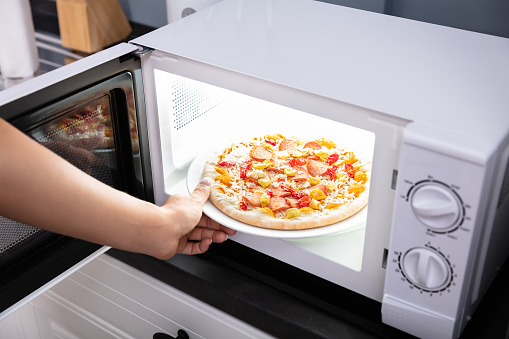 Close-up Of A Happy Woman Baking Pizza In Microwave Oven