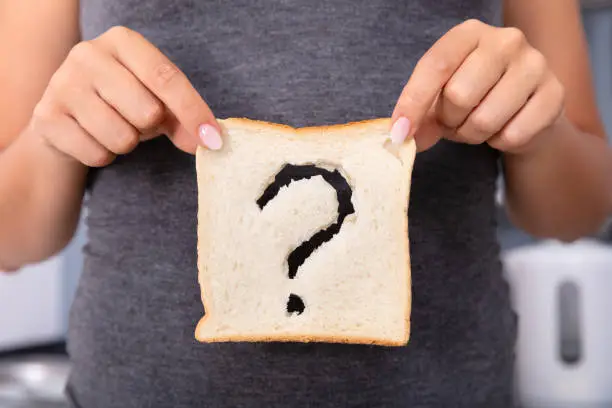 Mid-section Of A Woman Hands Holding Sliced Bread With Question Mark Sign