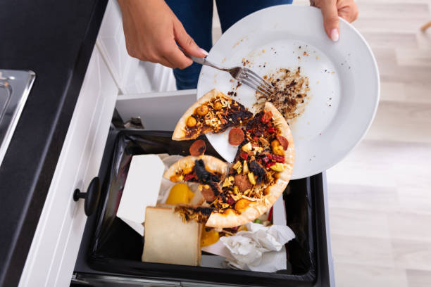 Person Throwing Pepperoni Pizza In Dustbin Close-up Of A Person Throwing Pepperoni Pizza On Plate In Dustbin food staple stock pictures, royalty-free photos & images