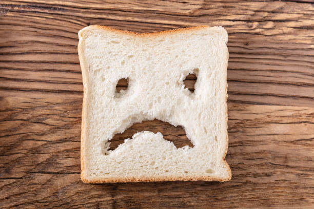 sad face on slice of bread - gluten allergy imagens e fotografias de stock