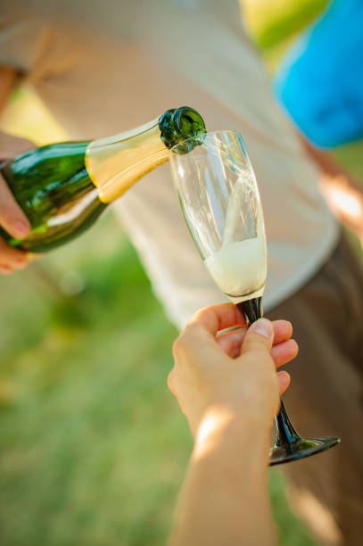 istock Close up on hand pouring champagne in a glass 1166082830