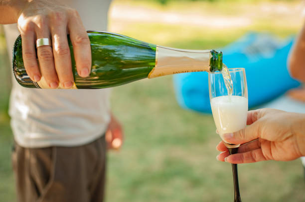 istock Close up on hand pouring champagne in a glass 1166082831