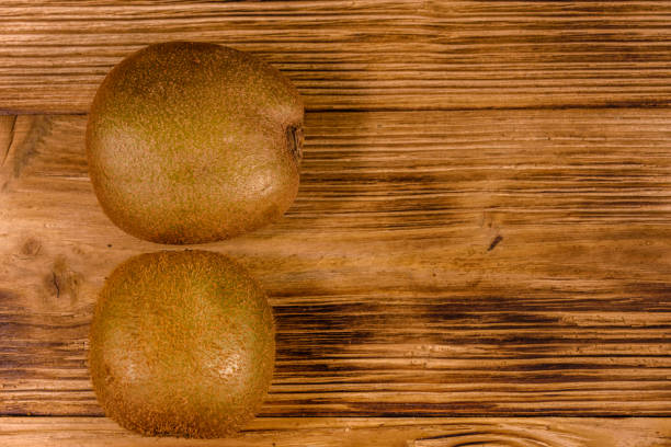 Two kiwi fruits on rustic wooden table. Top view