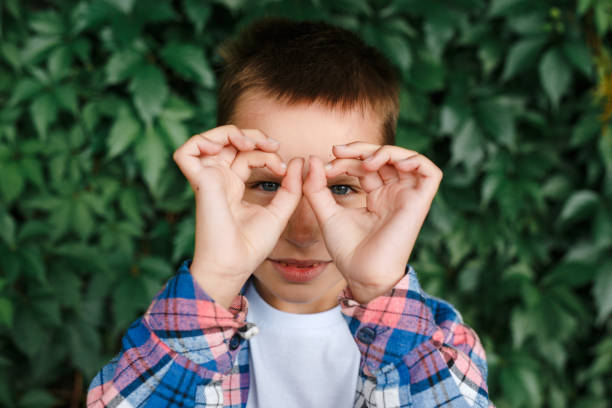 istock Little boy making OK gesture and looking through hand at camera outdoor 1166086367