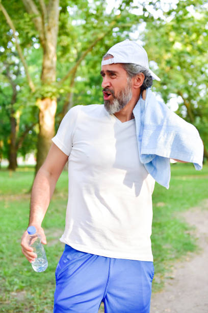 istock Middle-aged gray-haired man wipes himself with a towel after jogging 1166088450