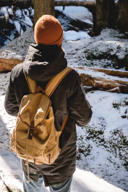 istock A bearded man in a hat and a backpack stands with his back in winter in a coniferous forest. 1166089690