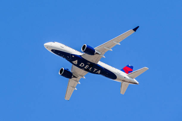 Delta Airlines aircraft in flight August 1, 2019 Santa Clara / CA / USA - Delta Airlines aircraft in flight; the Delta Logo visible on the airplanes' underbelly; blue sky background delta stock pictures, royalty-free photos & images