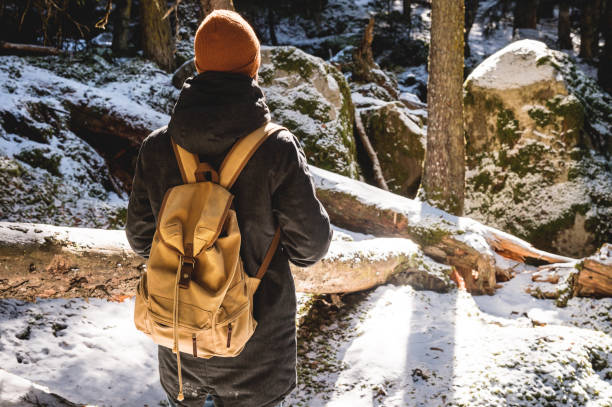 istock A bearded man in a hat and a backpack stands with his back in winter in a coniferous forest. 1166090396