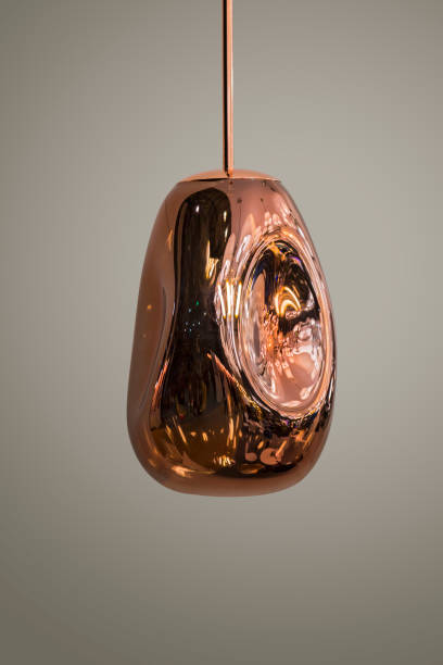istock Modern streamlined mirror copper chandelier. Metal shaped pendant lamp interesting form isolated on grey background. Loft style 1166092537