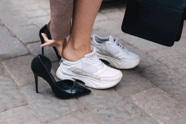 Barefoot business woman changing shoes from high heel to comfortable sneaker . Beautiful or comfortable shoes concept