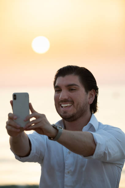 istock Man enjoying colorful sunset or sunrise, taking selfie 1166095497
