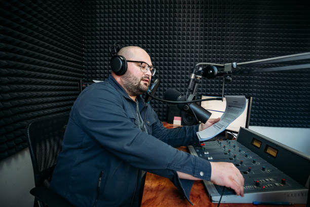 presentador de radio masculino parlante leer texto en papel en la estación de radio - dj de radio fotografías e imágenes de stock