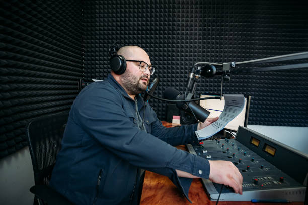 Talking male radio presenter read text on paper in radio station Talking male radio presenter read text on paper in radio station. radio dj stock pictures, royalty-free photos & images