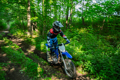 A young dirt bike rider tearing through the woods on his motorcycle scrambler.
