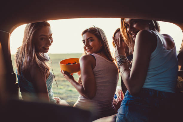 istock Four cheerful girlfriends enjoying snacks and relaxing while taking a break from their road trip 1166110685