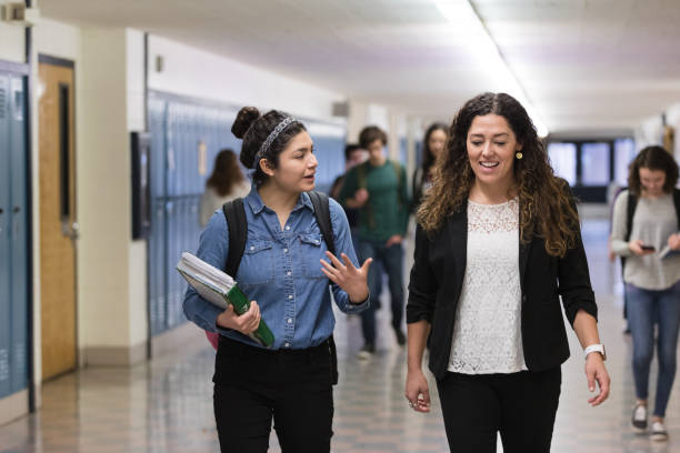 istock Ethnic teacher walking with one of her students down the hallway 1166110838