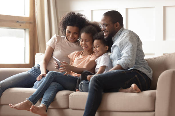 istock Happy black family with kids relax on sofa with tablet 1166111002