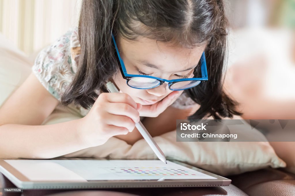 Asian school child girl using smart tablet device digital technology drawing on innovative touchscreen surface Child Stock Photo