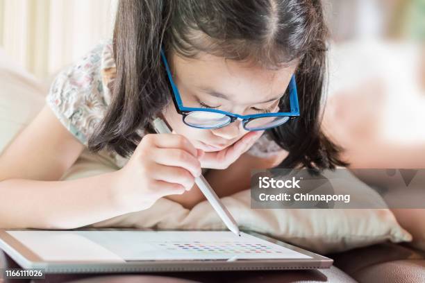Asian School Child Girl Using Smart Tablet Device Digital Technology Drawing On Innovative Touchscreen Surface Stock Photo - Download Image Now