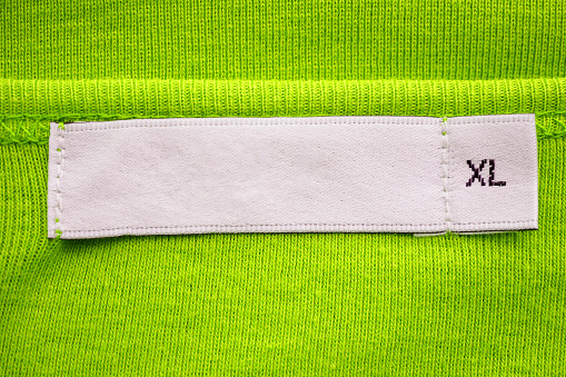 Blank white clothes tag label with XL size on new green shirt
