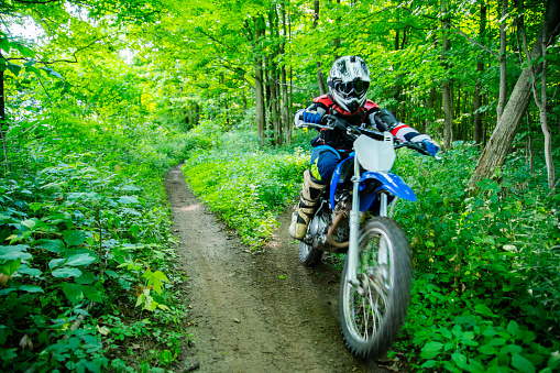 A young dirt bike rider tearing through the woods on his motorcycle scrambler.