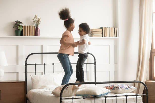 hermano y hermana negros activos saltan juntos a la cama - colchones para hermanos fotografías e imágenes de stock