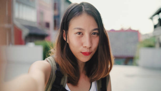 istock Cheerful beautiful young Asian backpacker blogger woman using smartphone taking selfie while traveling at Chinatown in Beijing, China. Lifestyle backpack tourist travel holiday concept. Point of view. 1166115793