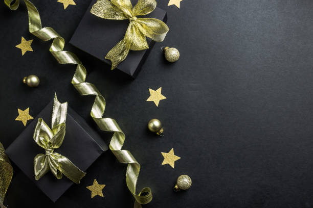 istock Black gift boxes with gold ribbon on black background. 1166116216