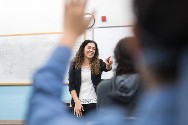 istock Ethnic teacher points to one of her students with a raised hand 1166116315