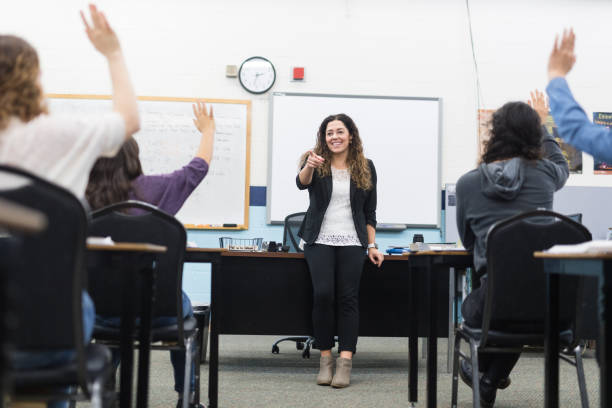 istock Ethnic teacher smiles while she waits to call on students with raised hands 1166117055