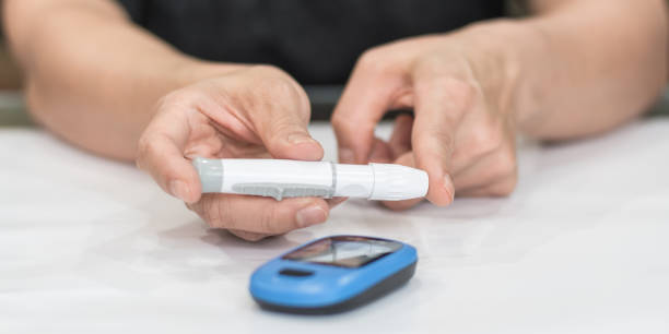 monitorización de la diabetes con prueba de azúcar en sangre, medición de glocuse en la yema del dedo del paciente de la mujer envejecida para analizar enfermedades deficientes en insulina, concienciación y control de la enfermedad diabética - diabetes human pregnancy women blood sugar test fotografías e imágenes de stock