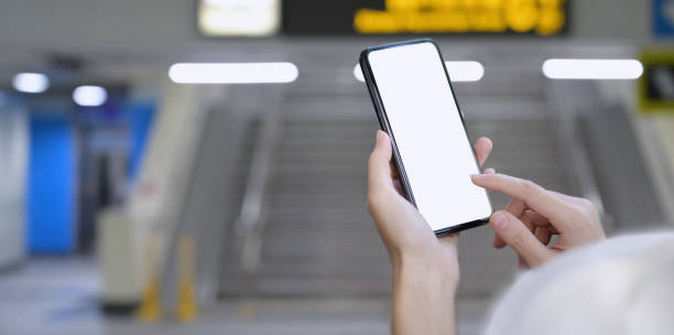 istock Woman holding blank screen smartphone at railway station 1166123292