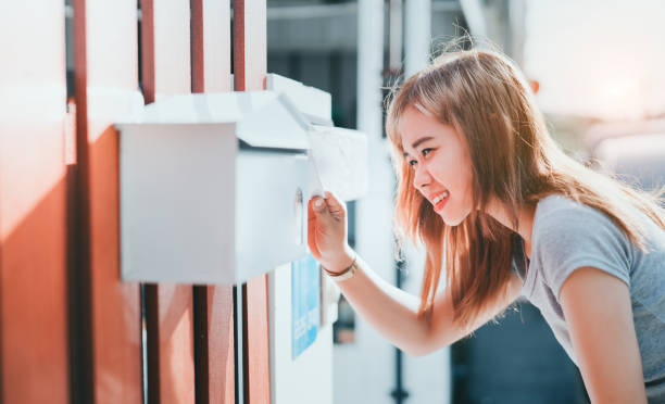 bella donna asiatica aperta casella di posta che controlla davanti a casa, le fatture del messaggio di consegna ordinano il concetto di mittente. - mailbox mail box open foto e immagini stock