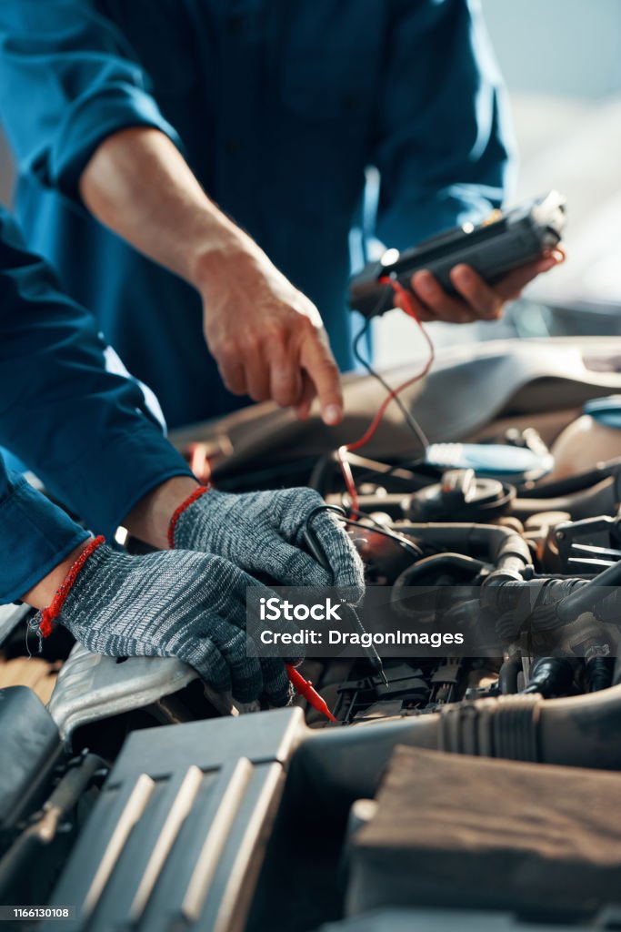 Mechanics using multimeter Mechanics using professional multimeter to check voltage level of car battery Car Stock Photo