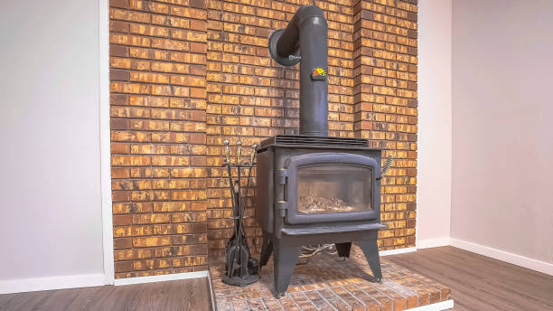 istock Panorama frame Black metal fireplave with glass door and pipe installed against a brick wall 1166130824