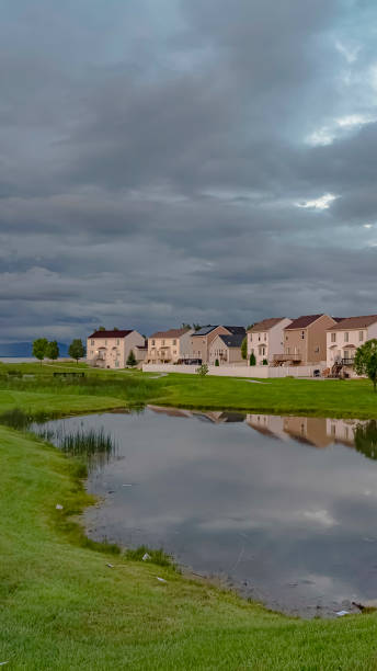 istock Vertical frame Scenic neighborhood park with a shiny pond and pathway under an overcast sky 1166136911