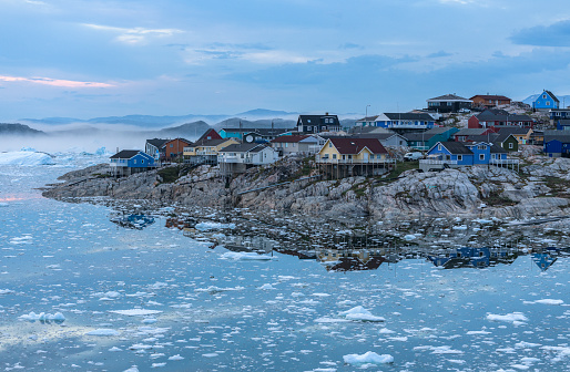 View from the end of the Ilulissat Icefjord to the town Ilulissat at the Disko Bay in western Greenland at midnight in July.