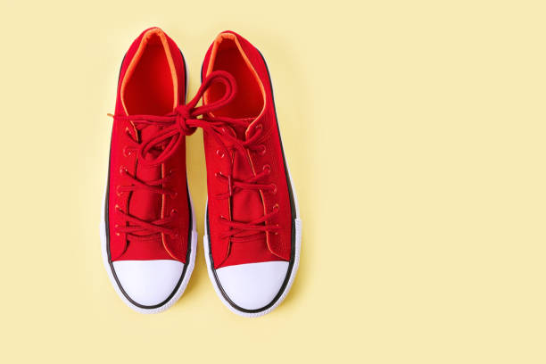 istock New red sneakers on yellow background with copy space. 1166145757