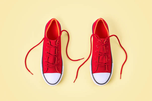 istock New red sneakers with shoelaces on yellow background with copy space. 1166145770