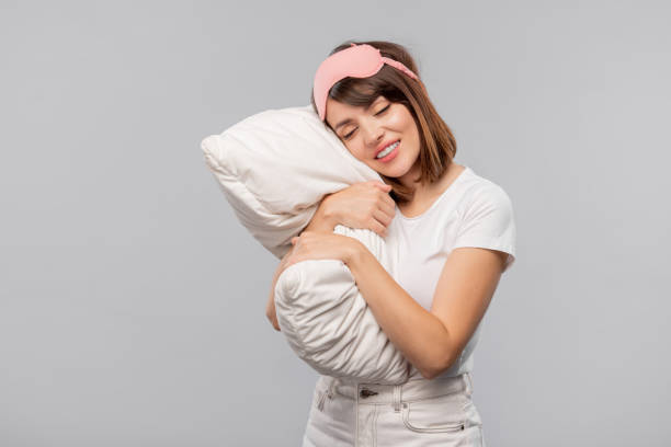 istock Happy girl in sleep-mask keeping her head on pillow while napping 1166148037