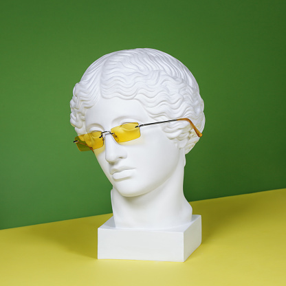 Plaster head model (mass produced replica of Head of an Amazon) wearing yellow eyeglasses