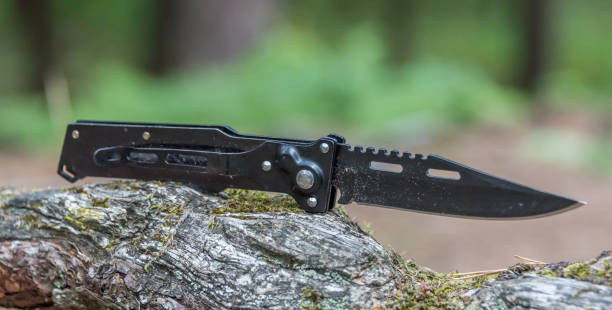 istock Black Metal Switchblade on a Tree Branch in a Forest 1166151301