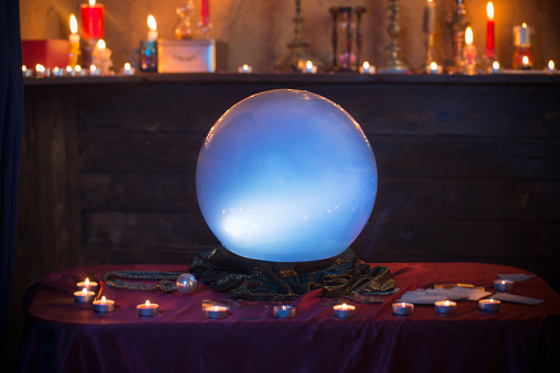 Bola de cristal mágico con velas ardientes en la mesa photo