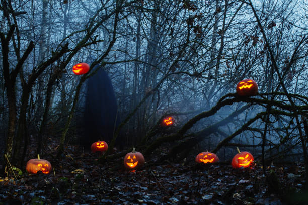 istock ghost with halloween pumpkins in night forest 1166152271