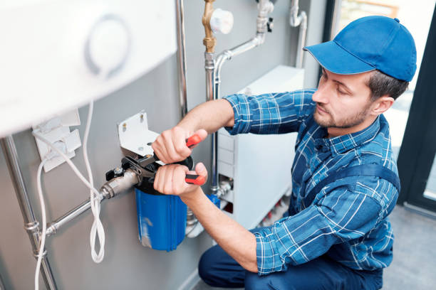 Young man in workwear using pliers while installing water filtration system Young man in workwear using pliers while installing water filtration system in the kitchen of client filtration stock pictures, royalty-free photos & images